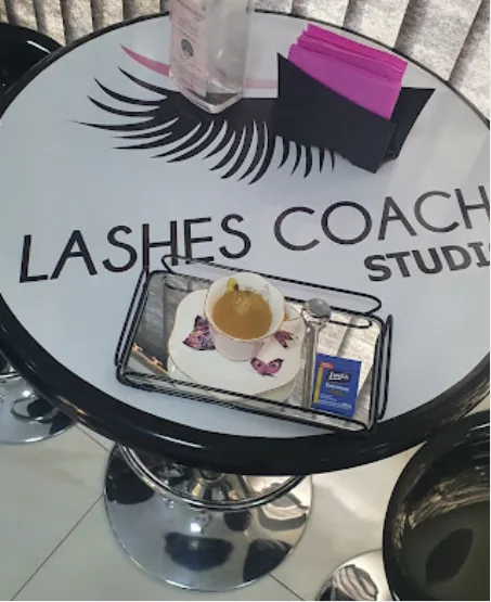 Mesa do estúdio com logo Lashes Coach Studio e cappuccino servido às clientes